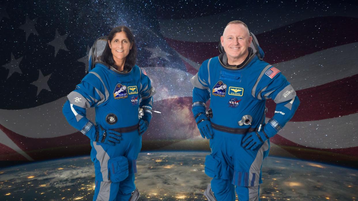  Two astronauts pose for a portrait in blue spacesuits. 