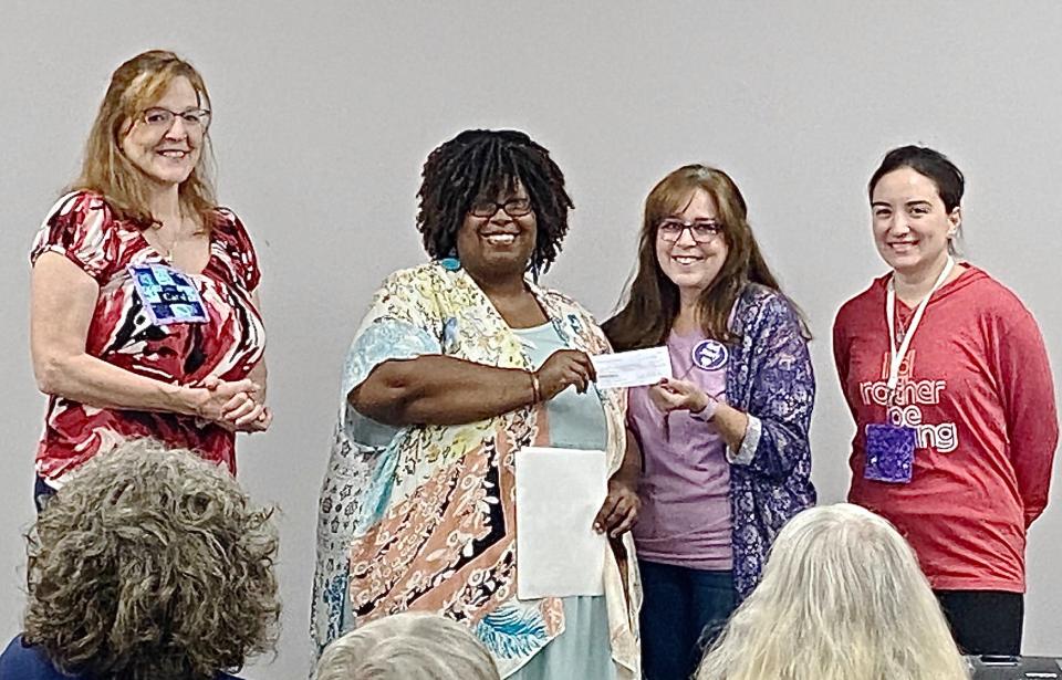 Members of the Antietam Quilt Guild present Dierdre Norris, second from left, with a check for more than $13,000 raised from raffling a quilt.