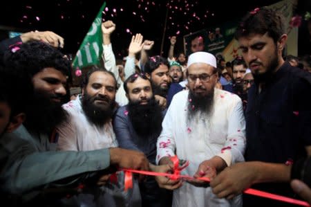 Hafiz Muhammad Saeed, chief of the Islamic charity organisation Jamaat-ud-Dawa (JuD), cuts a ribbon to inaugurates an election office of the newly formed political party Allah-o-Akbar Tehreek, in Lahore Pakistan July 14, 2018. Picture taken July 14, 2018. REUTERS/Mohsin Raza