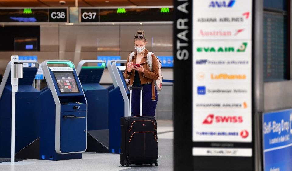 <p>A woman checks her cellphone by self check-in kiosks on the departures level of Los Angeles International Airport (LAX) on May 27, 2021 in Los Angeles.</p> (AFP via Getty Images)