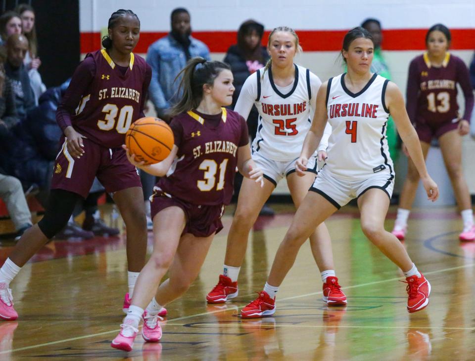 St. Elizabeth's Giovanna Cutler handles the ball on the perimeter as teammate Makayla Sullivan (30) and Ursuline's Norah McGlinchey (25) and Olivia O'Hara watch in the second half of Ursuline's 66-47 win at Ursuline Academy, Tuesday, Dec. 5, 2023.