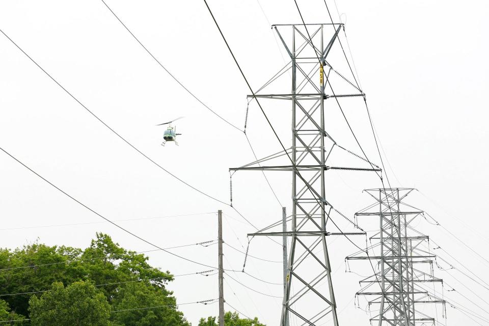 A helicopter flies close to high-voltage transmission structures to inspect them. Transmission structures, lines and equipment in Monroe County will be inspected by helicopter Sept. 26-Oct. 1 and Oct. 2-4, weather permitting.