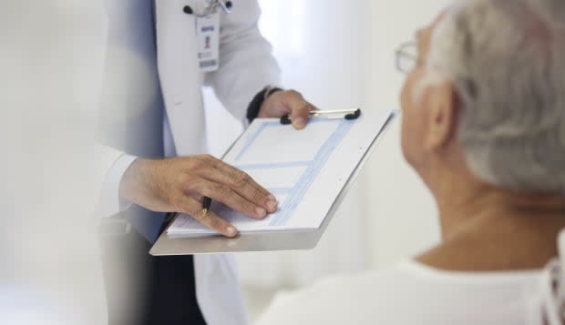 Doctor showing medical chart to patient in hospital room