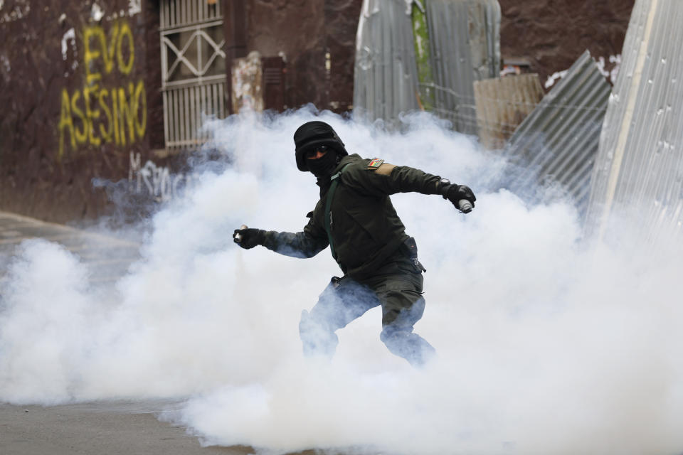 A Bolivian police officer hurls tear gas at backers of former President Evo Morales during clashes, in La Paz, Bolivia, Wednesday, Nov. 13, 2019. Bolivia's new interim president Jeanine Anez faces the challenge of stabilizing the nation and organizing national elections within three months at a time of political disputes that pushed Morales to fly off to self-exile in Mexico after 14 years in power. (AP Photo/Natacha Pisarenko)