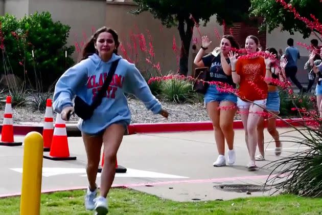 A girl runs as other shoppers leave with their hands up after police responded to Saturday's mass shooting north of Dallas.