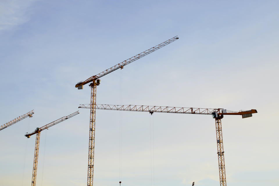 Cranes of a construction site against blue sky