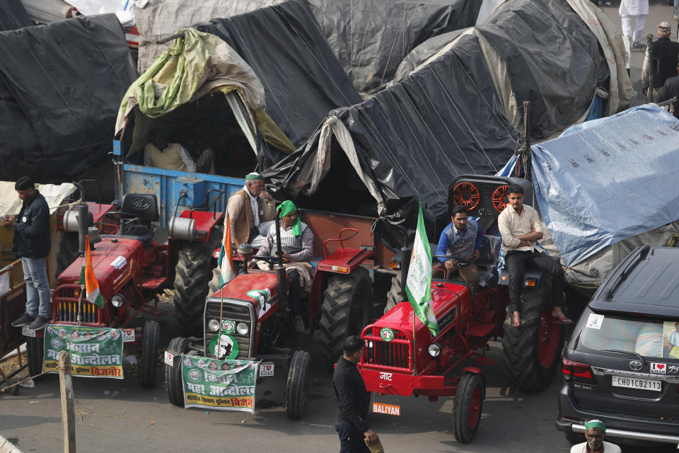 Indian farmers sit on their tractors after arriving at the Delhi-Uttar Pradesh border for Tuesday's tractor rally in New Delhi, India, Monday, Jan. 25, 2021. Thousands of farmers gathered on the borders of Delhi for a massive tractor rally on Tuesday against the three contentious farm laws when India will celebrate its Republic day with a military and cultural parade. The two-month-old old blockade of highways connecting the capital with the country's north continues as the talks have remained deadlocked with the government refusing to scrap the new agricultural reform laws which the farmers say will benefit large corporations. (AP Photo/Manish Swarup)