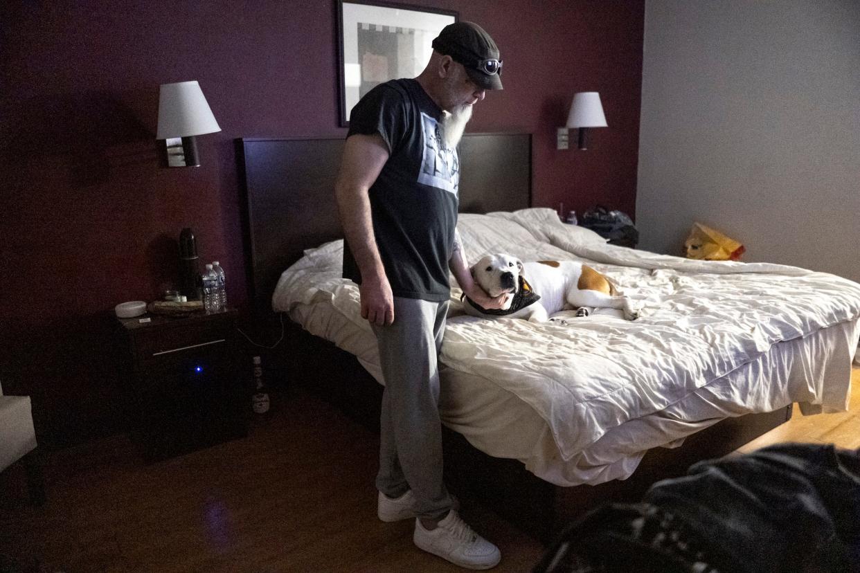 In a March 2023 photo, Steve Ison pets Frankie, his gator pit bull, in the hotel room he had been living in since leaving Latitude Five25.