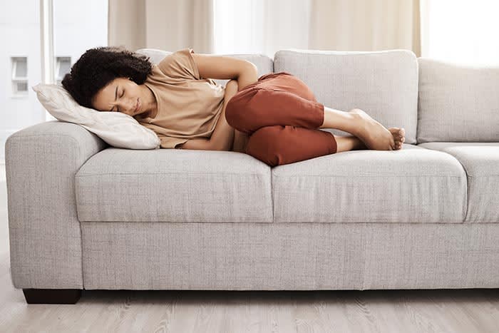 mujer con dolor tumbada en el sofá