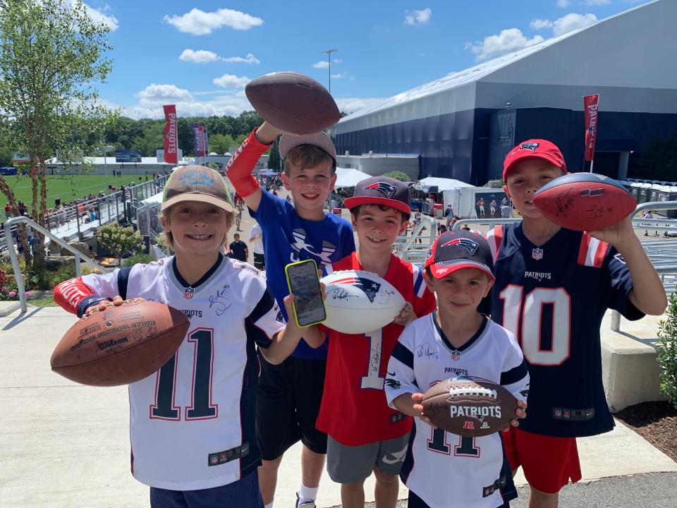 Five football fans from Marlborough show off their autographed gear at Patriots training camp at Gillette Stadium in Foxborough on Aug. 1, 2022.