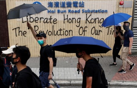 Demonstrator walk past a graffiti as they march during a protest in Hong Kong