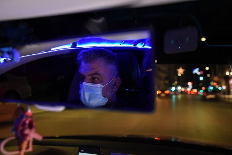 Greek driver Konstantinos Bekios, who has turned his taxi into a 'night club', is reflected in the rear view mirror in Thessaloniki