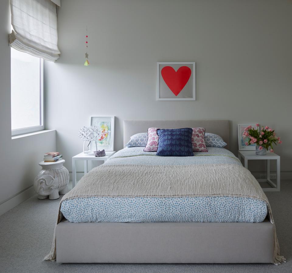 Accent pillows and a bright red heart add a splash of color to this neutrally toned children’s bedroom.