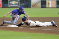 Texas Rangers third baseman Charlie Culberson, left, makes the tag on Houston Astros runner Alex Bregman, right, who loses his helmet on the contact during the first inning of a baseball game Thursday, May 19, 2022, in Houston. Bregman was trying to advance from first on a single by Aledmys Diaz. (AP Photo/Michael Wyke)