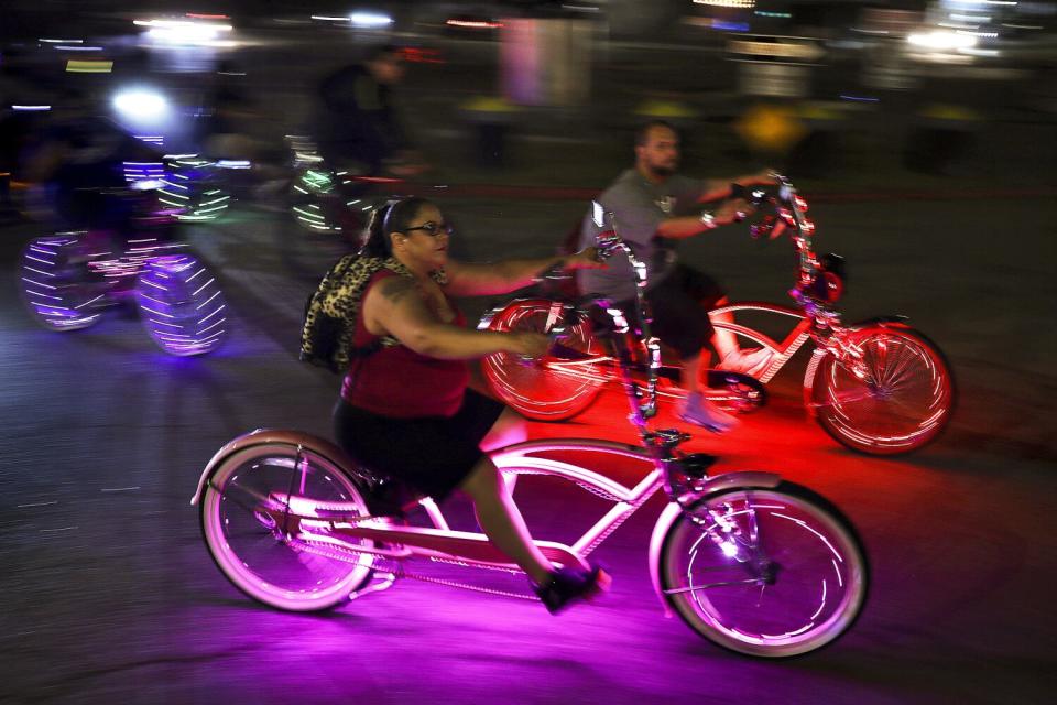 nighttime shot of people riding bikes with colorful lights on them