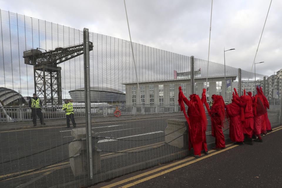 Red Rebel Brigade climate protesters demonstrate by the security fencing outside the Scottish Event Campus, the venue for the COP26 U.N. Climate Summit in Glasgow, Scotland, Tuesday, Nov. 2, 2021. The U.N. climate summit in Glasgow gathers leaders from around the world, in Scotland's biggest city, to lay out their vision for addressing the common challenge of global warming. (AP Photo/Scott Heppell)