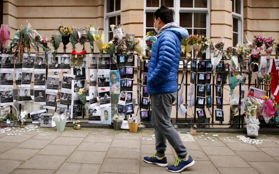 A man looks at floral tributes and pictures of the victims of pro-democracy protests attached to railings outside the embassy of Myanmar in London - Anadolu