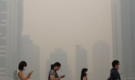 Office workers wearing masks make their way to work in Singapore's central business district in this June 21, 2013 file photograph. REUTERS/Edgar Su/Files