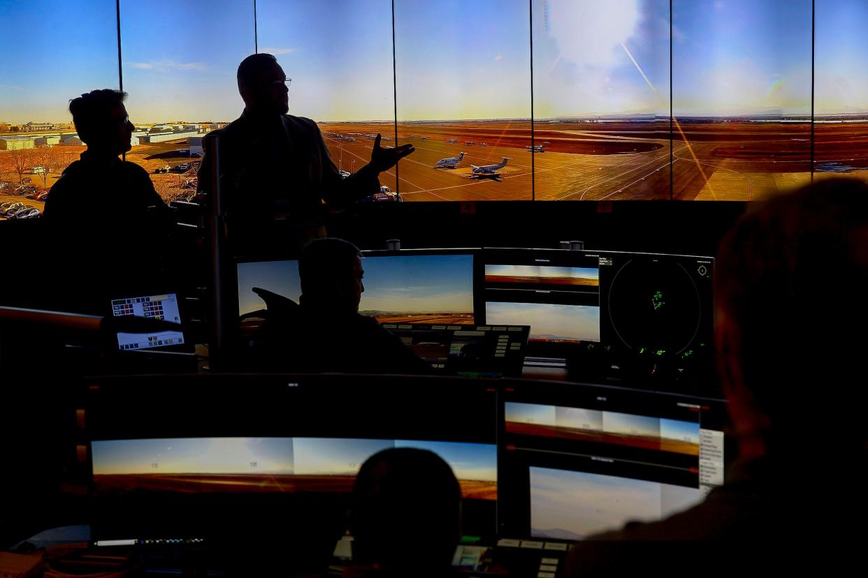 Former airport manager Jason Licon shows a tour group the wall-sized array of monitors used for the airport's remote air traffic control tower at the Northern Colorado Regional Airport in Loveland in 2018.