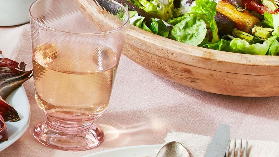 green salad with roasted carrots on top in a wooden bowl on a table