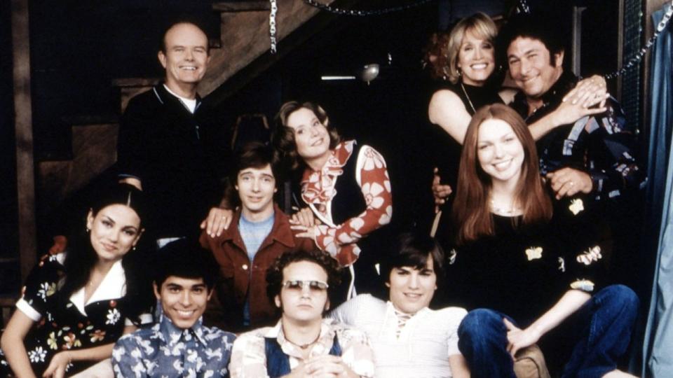 THAT ’70S SHOW: Mila Kunis, Wilmer Valderrama, Ashton Kutcher; standing from left: Kurtwood Smith, Topher Grace, Debra Jo Rupp, Tanya Roberts, Laura Prepon, Don Stark. ©20th Century Fox Film Corp. / courtesy Everett Collection.