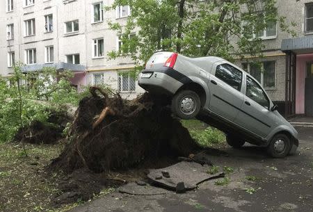 A view shows a car lifted by the roots of a tree, which was toppled during a heavy storm, in Moscow, Russia, May 29, 2017. REUTERS/Alexander Panchenko