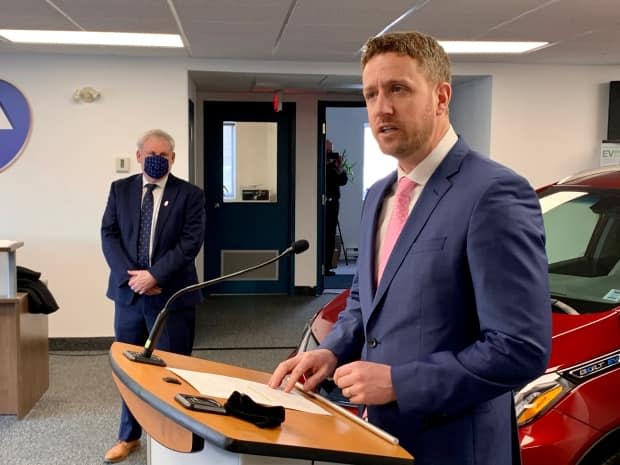 Premier Iain Rankin make an announcement Wednesday flanked by Environment and Climate Change Minister Keith Irving and an electric vehicle.  (Paul Palmeter/CBC - image credit)