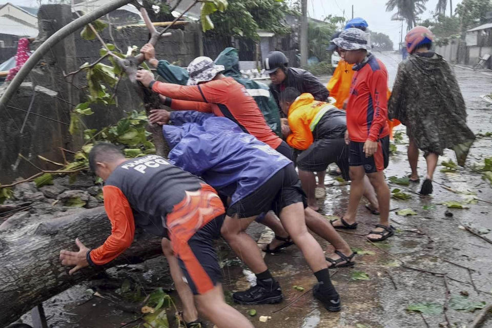 In this photo provided by the Philippine Coast Guard, Coast Guard personnel push a toppled tree caused by Typhoon Doksuri as they clear roads in Claveria, Cagayan province, northern Philippines on Wednesday July 26, 2023. Typhoon Doksuri ripped off tin roofs from homes, engulfed low-lying villages in flood, knocked down power and displaced more than 12,000 people Wednesday as it smashed into a small island and lashed northern Philippine provinces overnight with ferocious wind and rain, officials said. (Philippine Coast Guard via AP)