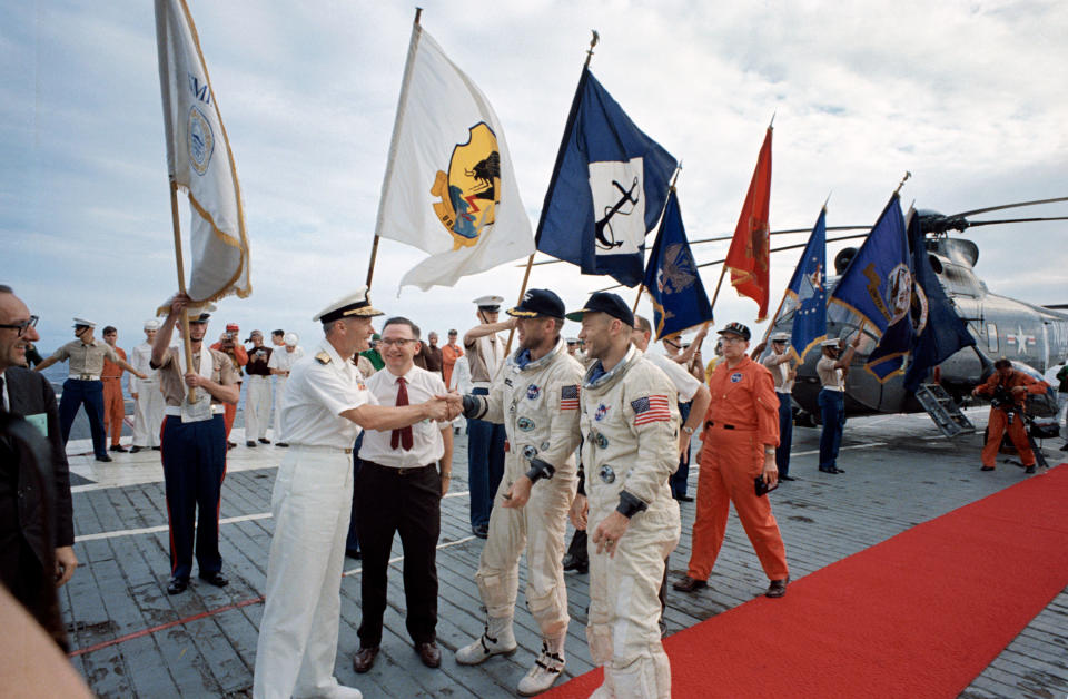 Astronauts James A. Lovell Jr. (left), command pilot, and Edwin E. Aldrin Jr., pilot, receive official welcome as they arrive aboard the aircraft carrier USS Wasp. Gemini-12 splashed down in the Atlantic Ocean recovery area at 2:21 p.m. (EST), Nov. 15, 1966.<span class="copyright">NASA</span>