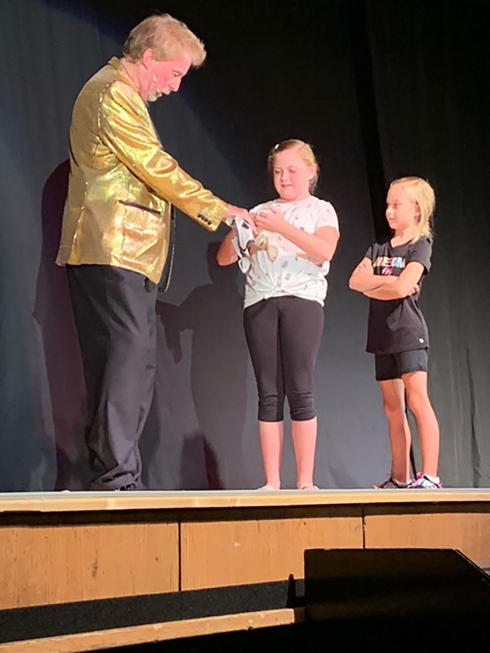 Magician David Seebach gets help from Niles residents Libby and Ella Cornelius during a card trick at Saturday's showcase performance at Colon High School. The four-day Abbott's Magic Get-Together concluded Saturday.
