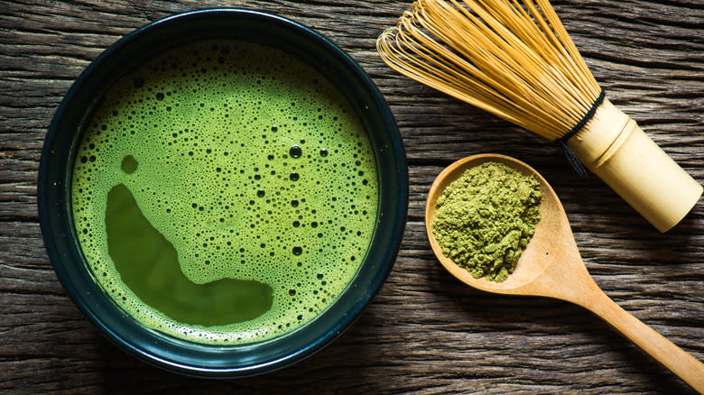 Bowl of matcha tea with wooden spoon of matcha powder