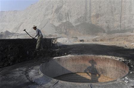 A worker smashes coal as he prepares to burn limestone at a nearby furnace inside a limestone mine in Quzhou, Zhejiang province, in this October 12, 2012 file photo. REUTERS/Stringer/Files