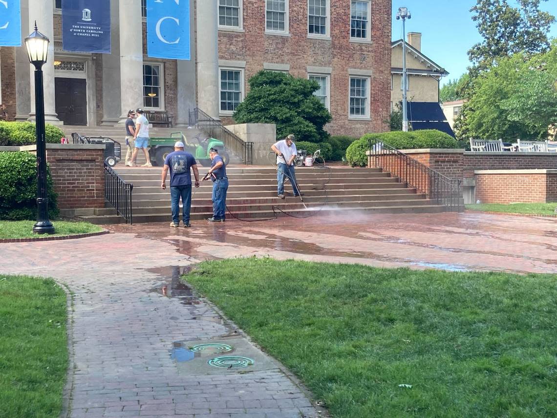 Maintenance workers pressure-wash the steps to UNC’s South Building after protesters splattered red paint on them earlier this afternoon.