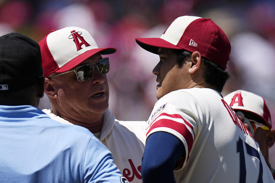 Los Angeles Angels managers Phil Nevin, center, talks with starting pitcher Shohei Ohtani before taking him out of the game due to arm fatigue during the second inning in the first baseball game of a doubleheader Wednesday, Aug. 23, 2023, in Anaheim, Calif. (AP Photo/Mark J. Terrill)