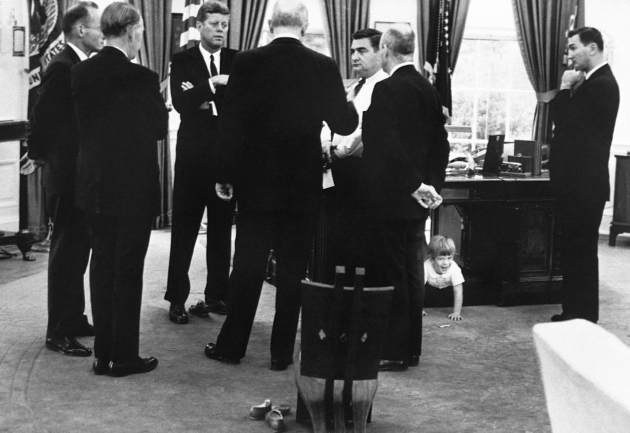 president kennedy meets with advisors in the oval office, while his son, john jr plays under the desk october 14, 1963