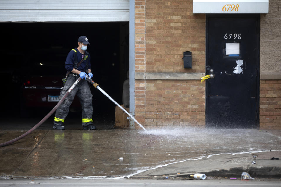 A Chicago firefighter cleans up blood as Chicago police officers work the scene of a fatal shooting early Sunday, March 14, 2021, in the Park Manor neighborhood of Chicago. Authorities say gunfire erupted at a party on Chicago’s South Side early Sunday morning. (Erin Hooley /Chicago Tribune via AP)