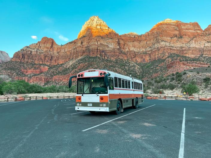 The van parked in a parking lot by large, orange natural landmarks