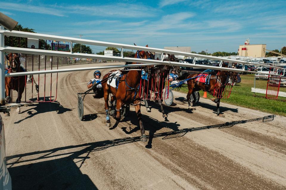 Harness racers follow the starter truck's gates, run by Mike Woebkenberg, of Woebkenberg Starting Gates, at the Tuscarawas County Fair. The starting system requires a driver and a starter in the truck. Control of the accelerator and brake are eventually controlled by the starter, sitting backwards and elevated from the rear of the cab, while the person in the actual driver's seat steers. Once the gate retracts and the racers are off, full control is ceded back to the driver.