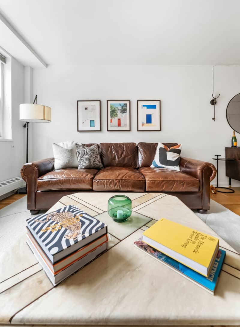 White living room with brown leather sofa and large marble coffee table with books