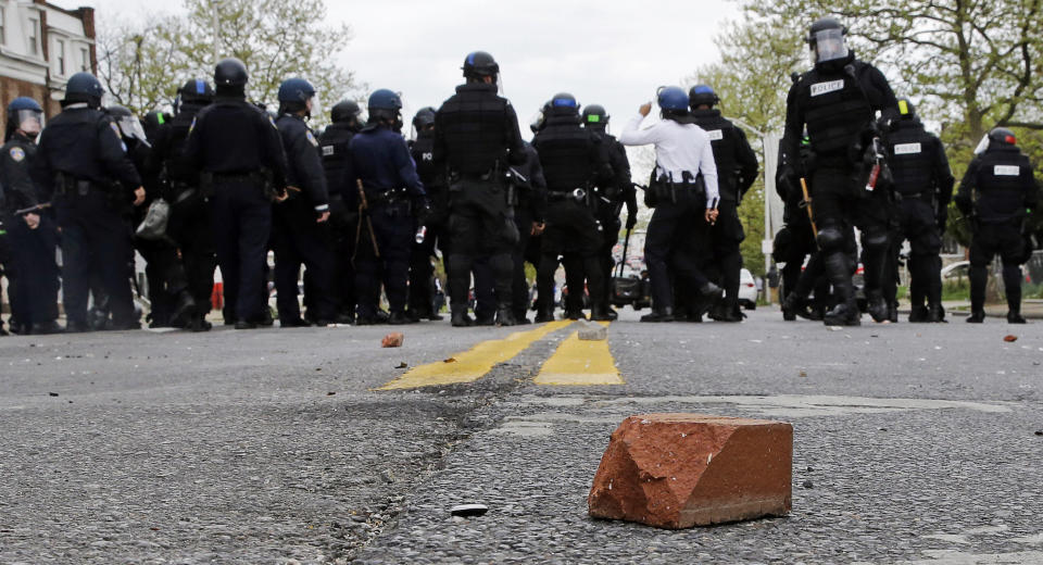 A brick sits on a street as police standby, Monday, April 27, 2015, during a skirmish with demonstrators after the funeral of Freddie Gray in Baltimore. Gray died from spinal injuries about a week after he was arrested and transported in a Baltimore Police Department van. (AP Photo/Patrick Semansky)