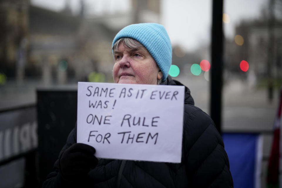 An anti-Brexit protester holds up an anti-government placard by Parliament Square, in London, Tuesday, Jan. 25, 2022. London police said Tuesday they were investigating Downing Street lockdown parties in 2020 to determine if U.K. government officials violated coronavirus restrictions, putting further pressure on Prime Minister Boris Johnson. (AP Photo/Matt Dunham)