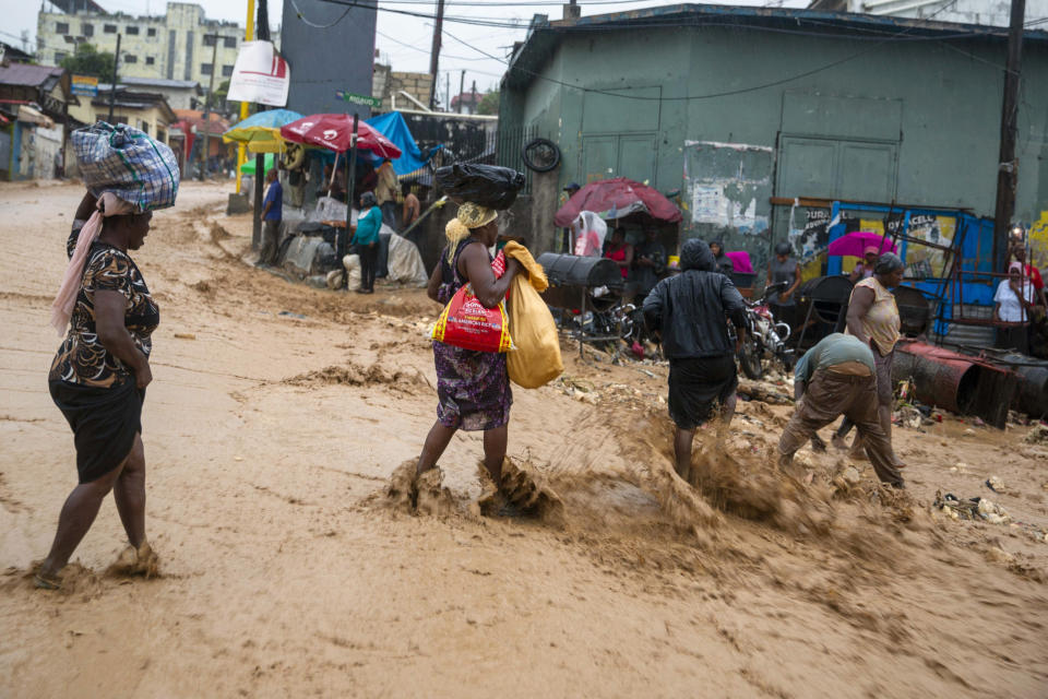 Street vendors cross a flooded street during Tropical Storm Laura in Port-au-Prince, Haiti, Sunday, Aug. 23, 2020. Tropical Storm Laura battered the Dominican Republic and Haiti and heading for a possible hit on the Louisiana coast as a hurricane, along with Tropical Storm Marco. (AP Photo/Dieu Nalio Chery)