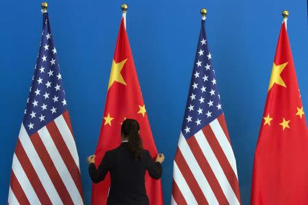 A Chinese woman adjusts a Chinese national flag next to U.S. national flags before a Strategic Dialogue expanded meeting, part of the U.S.-China Strategic and Economic Dialogue (S&ED) held at the Diaoyutai State Guesthouse in Beijing, July 10, 2014. REUTERS/Ng Han Guan/Pool