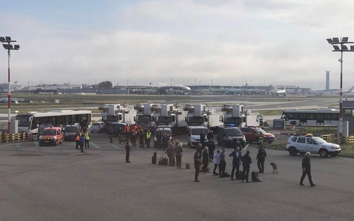 Passengers wait on the concrete at Charles de Gaulle airport in Paris  - PA