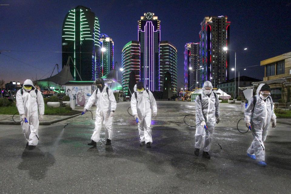 Municipal workers wearing protective suits spray disinfectant in an area in the center of Grozny, Russia, Monday, April 6, 2020. Ramzan Kadyrov, strongman leader of Russia's province of Chechnya, has taken extreme measures to fight the spread of the new coronavirus in the region, vowing Monday not to let anyone who is not a formal resident of Chechnya into the area.The new coronavirus causes mild or moderate symptoms for most people, but for some, especially older adults and people with existing health problems, it can cause more severe illness or death. (AP Photo/Musa Sadulayev)