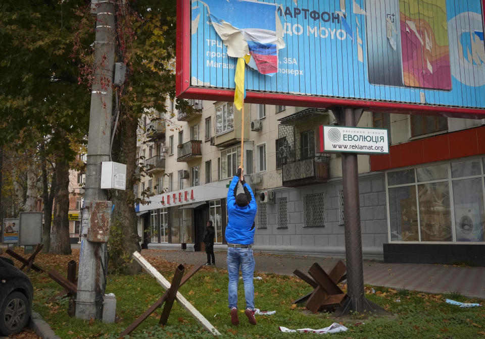 FILE - A local resident removes the Russian flag from a billboard in central Kherson, Ukraine, Sunday, Nov. 13, 2022. Amid the death and destruction war leaves in its wake, there are powerful dynamics and narratives: domination, besieged populations, occupation and their counterparts, resistance, freedom and liberation. Vast swaths of Western and Eastern Europe and the Soviet Union knew this well at various points of the 20th century. (AP Photo/Efrem Lukatsky, File)