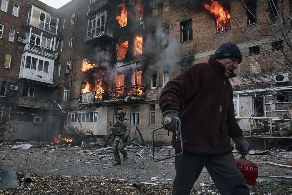 A local resident leaves his home after Russian shelling destroyed an apartment house in Bakhmut, Donetsk region, Ukraine, Wednesday, Dec. 7, 2022. (AP Photo/LIBKOS)