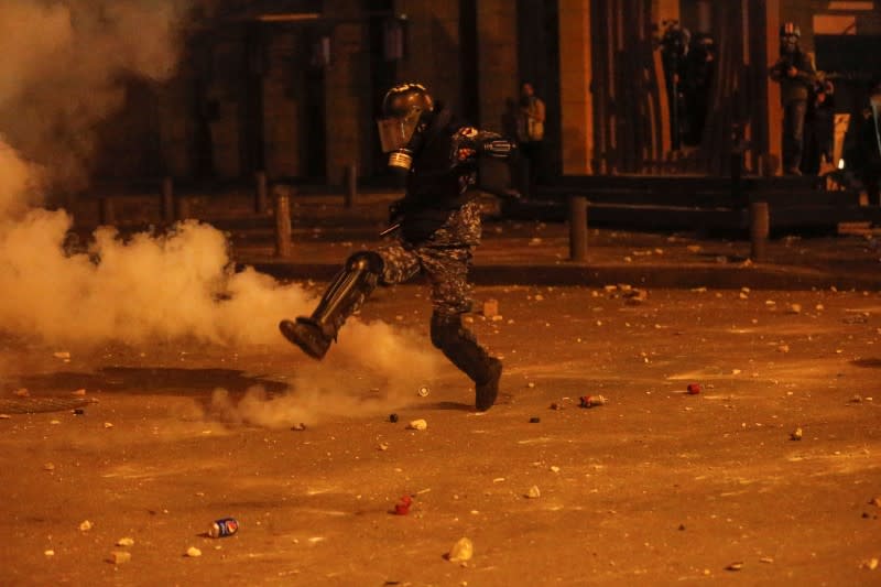 A riot police kicks a tear gas canister during a protest against a ruling elite accused of steering Lebanon towards economic crisis in Beirut