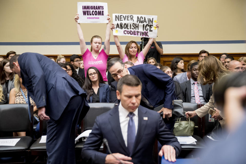 Activists with Code Pink hold up signs that read "Immigrants Welcome" and "Never Again Abolish ICE" as Acting Secretary of Homeland Security Kevin McAleenan arrives to testify before a House Committee on Oversight and Reform hearing on Capitol Hill in Washington, Thursday, July 18, 2019. (AP Photo/Andrew Harnik)