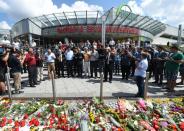 People pray on July 24, 2016 at a memorial in front of the Olympia Einkaufszentrum shopping centre in Munich where an 18-year-old went on a shooting rampage, killing nine